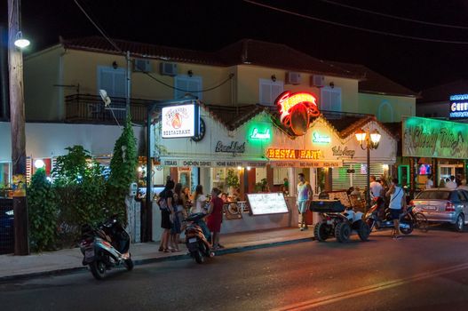 Laganas, Zakynthos Island, Greece - August 25, 2015: Colorful neons on the restaurant building at the main road of Laganas at night. Laganas is a very popular party destination in Greece.