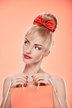Beauty fashion portrait loving woman thinking with shopping bag. Confidence sensual attractive pretty nude blonde sexy girl, Pinup hairstyle, red bow. Unusual playful. Romantic on pink, sale, discount