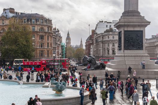 London, United Kingdom - November 8, 2014: Tourists visit Trafalgar Square on a cloudy day. It is one of the most popular tourist attraction in London, often considered the heart of London.