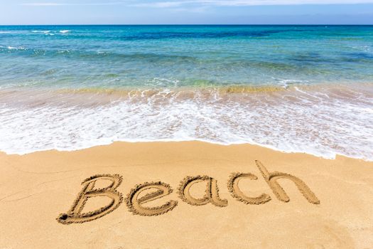 Word Beach written in sand of coast at sea