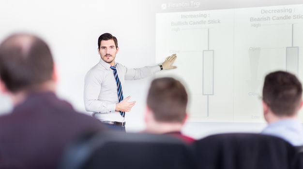 Business man making a presentation at office. Business executive delivering a presentation to his colleagues during meeting or in-house business training, explaining business plans to his employees.