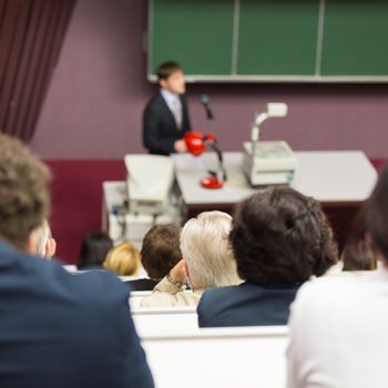 Lecturer at university. Healthcare expert giving a talk to medical faculty professors. Participants listening to lecture and making notes.