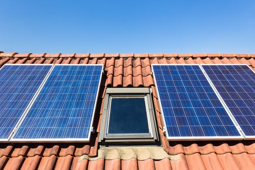 Solar panels and attic window with blue sky