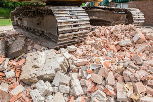 Metal caterpillars on heap of broken bricks of demolished house