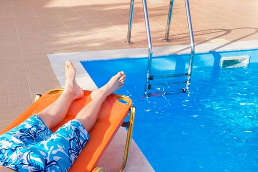 Caucasian teenage boy lying on stretcher near blue fswimming pool