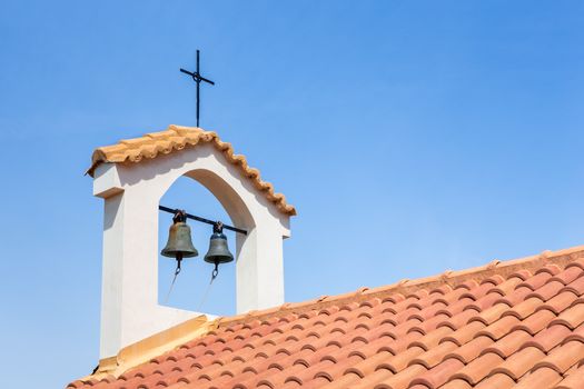 Churchtower on orange roof with bells and cross