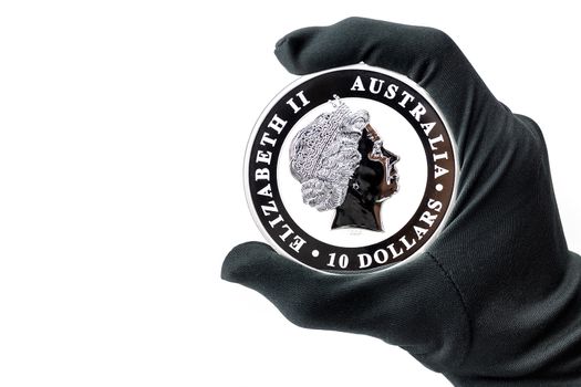 Hand in black glove holding large silver 10 dollars coin