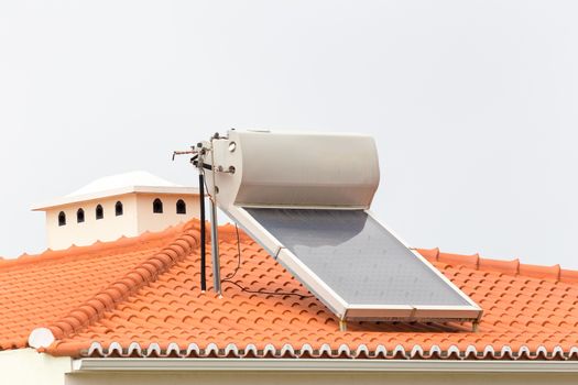 Hot water boiler with solar panel on roof of house