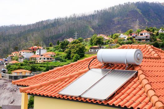 Water boiler with solar panels on roof of house in village of Madeira