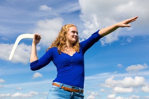 Young dutch woman throwing boomerang with blue sky