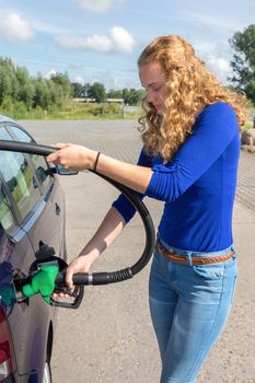 Young caucasian woman filling up tank of car with benzine
