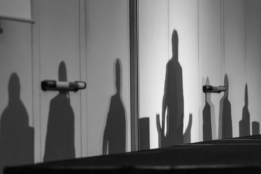 Abstract silhouettes of people at business meeting, Seminar event room with dark shadows in background. Leaders in the background business or policy concept. Black and white image.