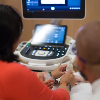 Female medical doctor students learning to do medical examination of patient with ultra sound scanner machine on ultrasound techniques workshop.