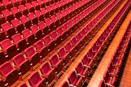 Rows of red color theatre chairs in conference room.