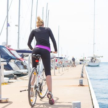 Young active woman cycling on pier in Rovinj marina, Istria, Croatia