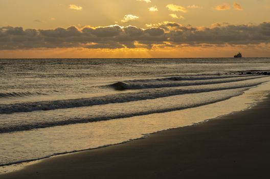 Sea-going vessel near the coast of Zoutelande in Netherlands at sunset
