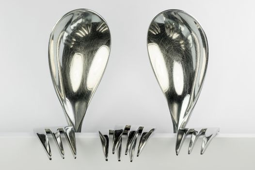 Metal spoons and three forks formed into two conceptual fantasy figures
