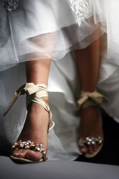 Wedding shoes on barefooted legs of the bride