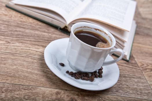 A cup of coffee with a book on a wooden background