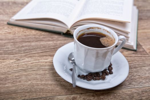 A cup of coffee with a book on a wooden background