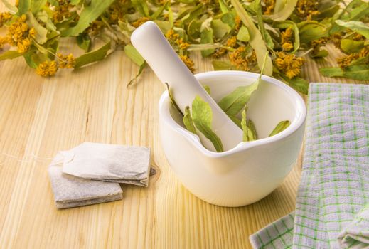 Conceptual image with tea bags filled with linden flowers powder, obtained by grinding them in a mortar. Natural content in a tea bag. Product idea.