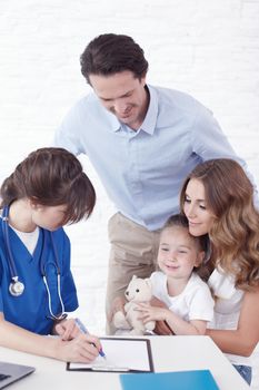 Young pediatrician doctor talking with girl and her parents