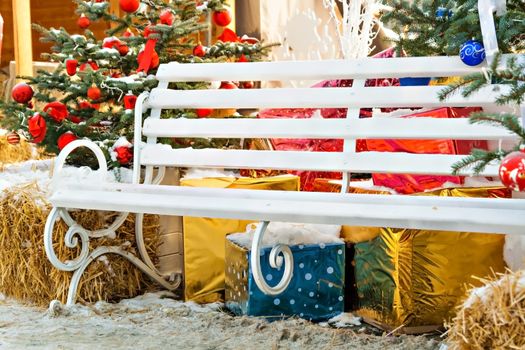 Christmas tree decorations, gifts, bench, hay outdoors.