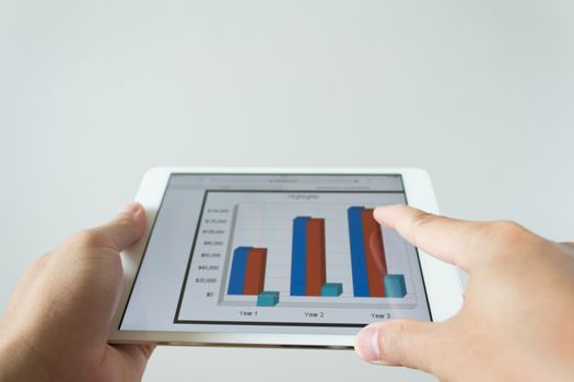 Businessman hand touching screen of tablet computer with market graph