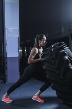 Concept: power, strength, healthy lifestyle, sport. Powerful attractive muscular woman CrossFit trainer doing giant tire workout at the gym