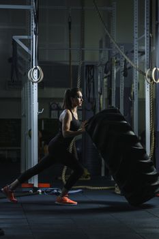 Concept: power, strength, healthy lifestyle, sport. Powerful attractive muscular woman CrossFit trainer doing giant tire workout at the gym