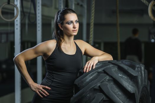 Concept: power, strength, healthy lifestyle, sport. Powerful attractive muscular woman CrossFit trainer doing giant tire workout at the gym