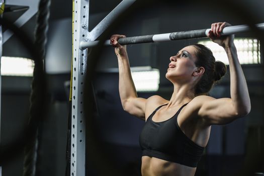 Concept: power, strength, healthy lifestyle, sport. Powerful attractive muscular woman CrossFit trainer do pull ups during workout at the gym