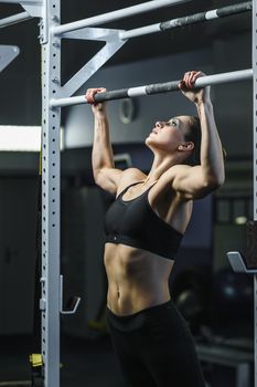 Concept: power, strength, healthy lifestyle, sport. Powerful attractive muscular woman CrossFit trainer do pull ups during workout at the gym