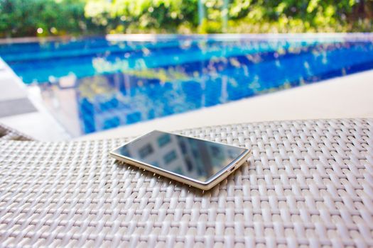 Smartphone put on armchair beside the pool means to get resting  away from business