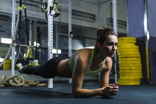 Concept: power, strength, healthy lifestyle, sport. Powerful attractive muscular woman CrossFit trainer stand in plank during workout at the gym