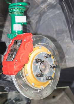 Front disk brake system on car in process of damaged tyre replacement. The rim is removed showing the front rotor and caliper.