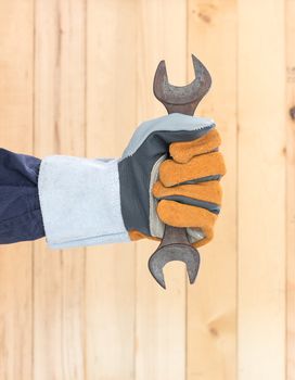 Working hand in glove holding a hammer with wall wood background
