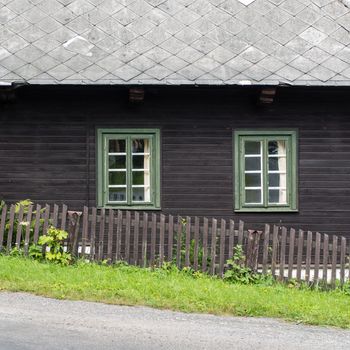 Authentic rustic nd brown mountain cottage front with windows and stones in Orlicke Mountains, Czech republic, Europe