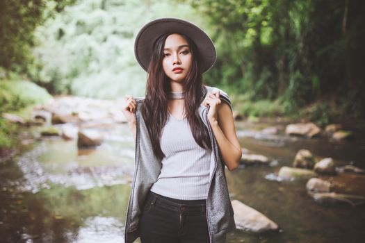 Beautiful asian woman smiling around the nature green and water.