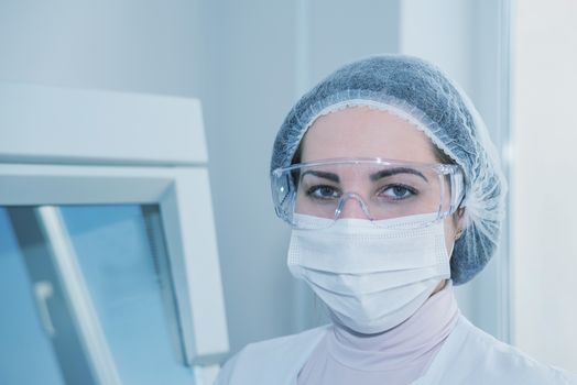 Woman scientist in a white protective clothing preparing for the experiments in the laboratory looking directly