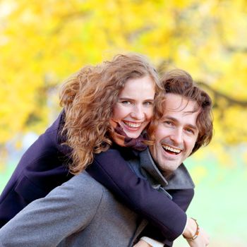 Happy couple hug in autumn park with yellow trees