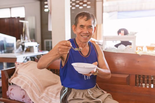 Senior Man smiling and eating rice at home.