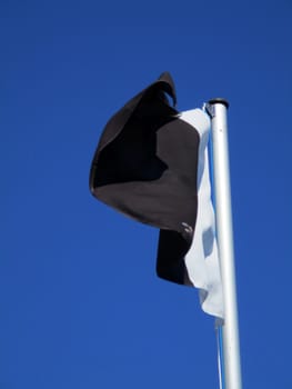 white and black flag flying in the blue sky