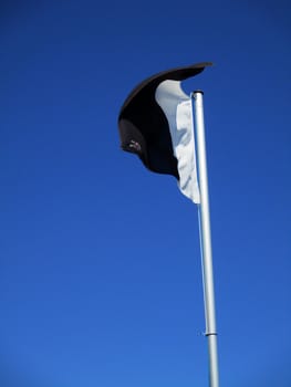 white and black flag flying in the blue sky