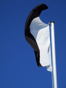 white and black flag flying in the blue sky