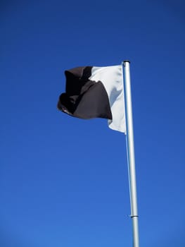 white and black flag flying in the blue sky