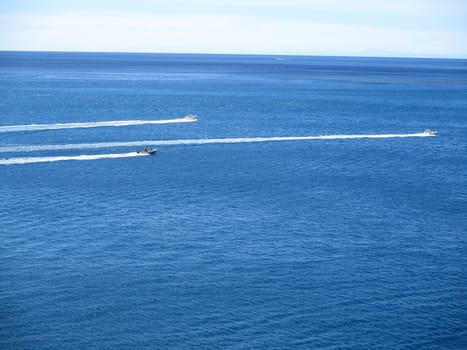 speed boats that leave a white strip in the blue sea