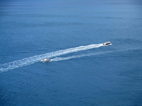 speed boats that leave a white strip in the blue sea