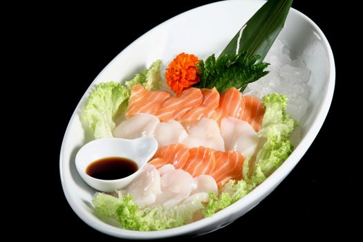 mixed sushi on a white plate, black background