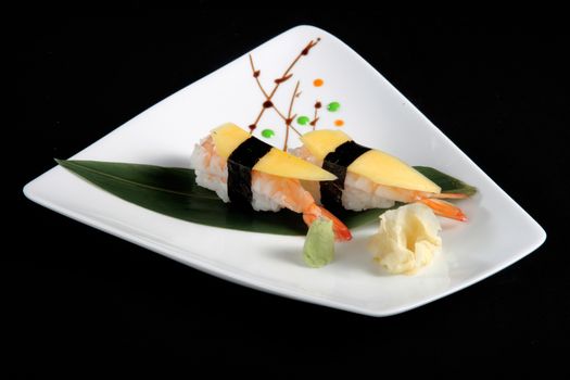 portion of sushi with vegetables on white plate, black background